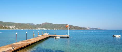 A wooden pier extending into calm blue waters with a clear sky.