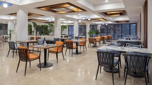 Un restaurante espacioso con varias zonas de comedor, amplios ventanales e iluminación moderna.