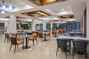 A spacious restaurant with multiple dining areas, large windows, and modern lighting fixtures. - DoubleTree by Hilton Bodrum Işıl Club Ultra All Inclusive Resort (Bodrum)