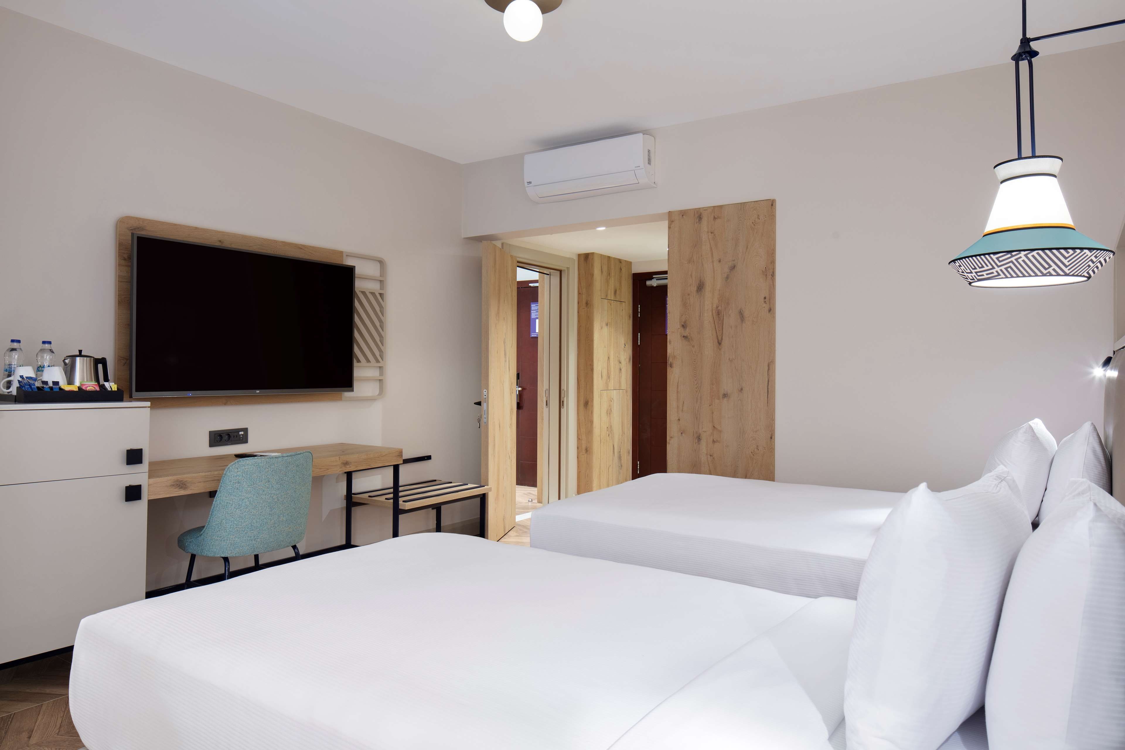Una habitación de hotel con dos camas, un escritorio, un televisor y una puerta de madera.