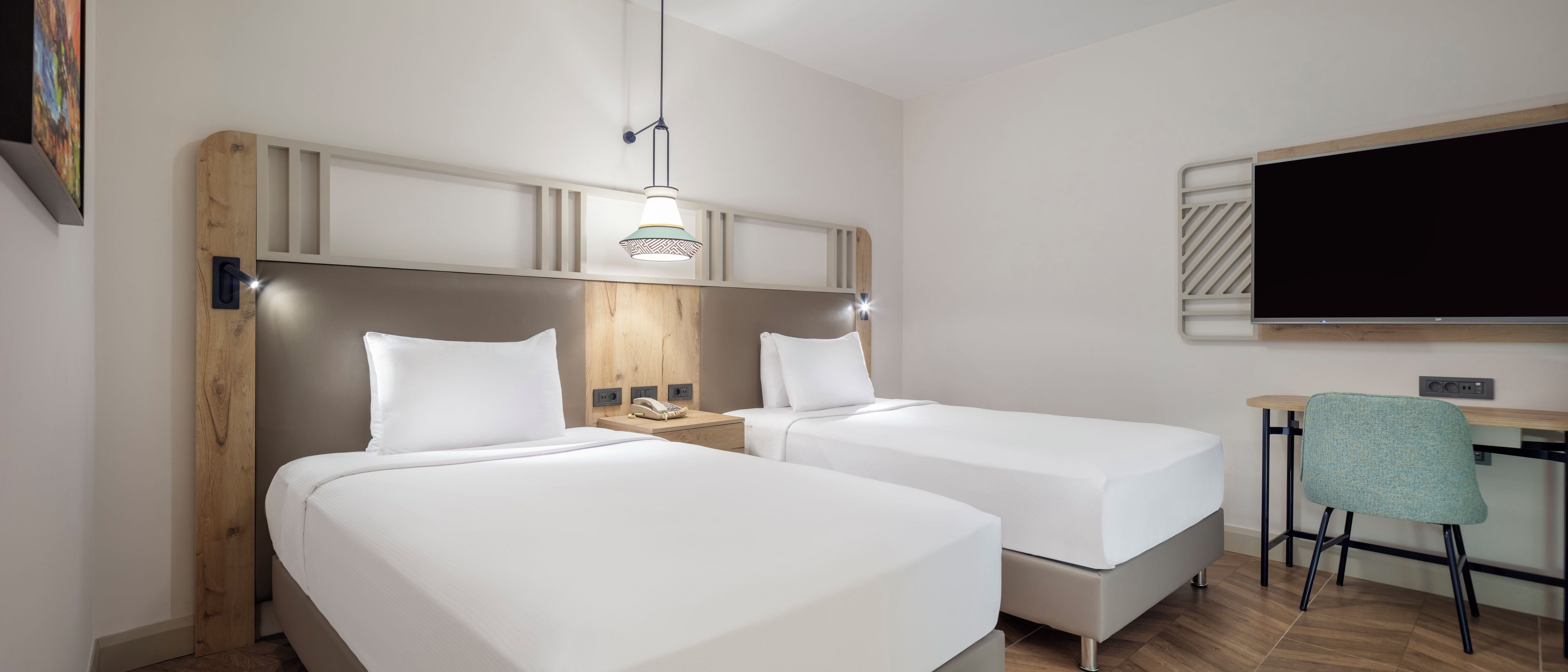 Una habitación de hotel con dos camas, un escritorio, una silla, un televisor y una lámpara.
