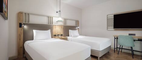Una habitación de hotel con dos camas, un escritorio, una silla, un televisor y una lámpara.