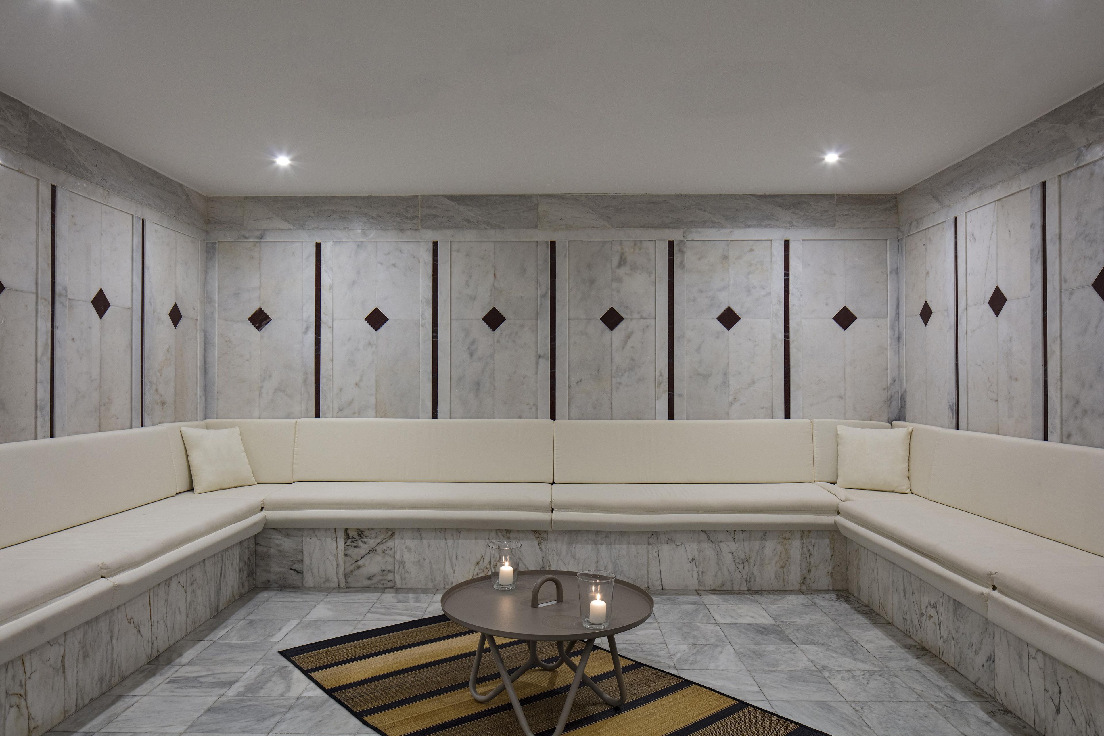 Un interior moderno con una pared de mármol, una zona de estar y una mesa redonda con velas.