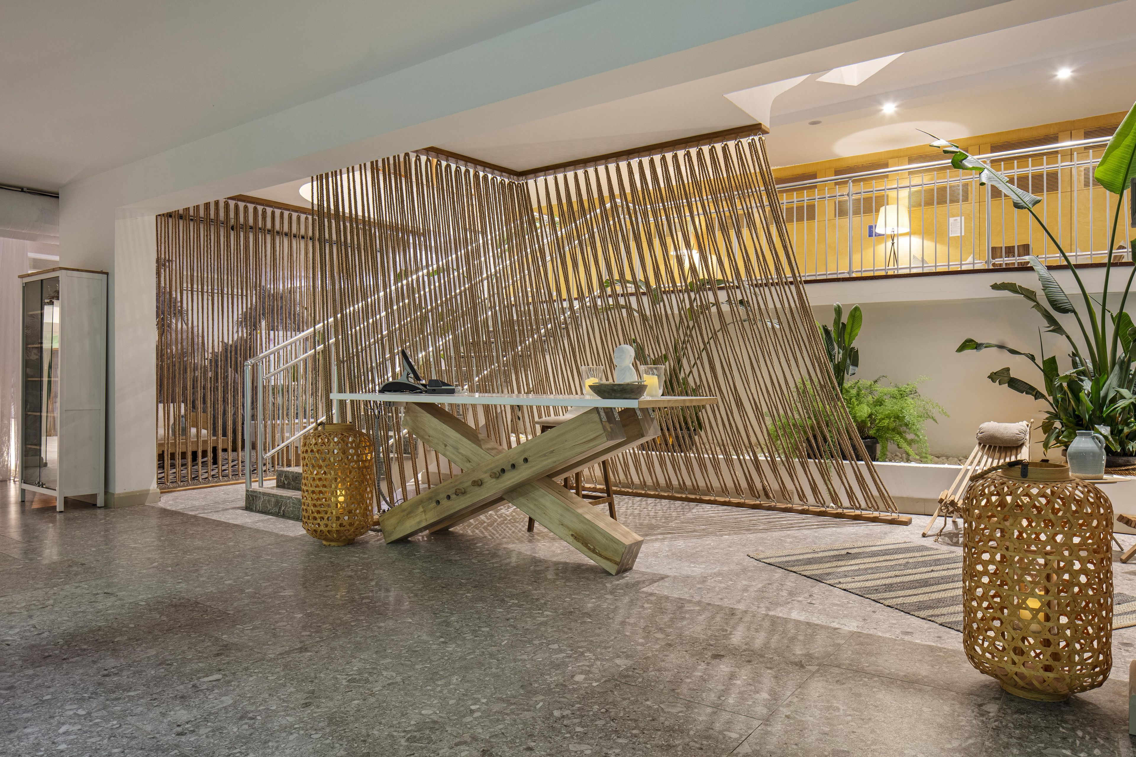 A modern interior with a glass-top table, a decorative wall, and a seating area with a plant.