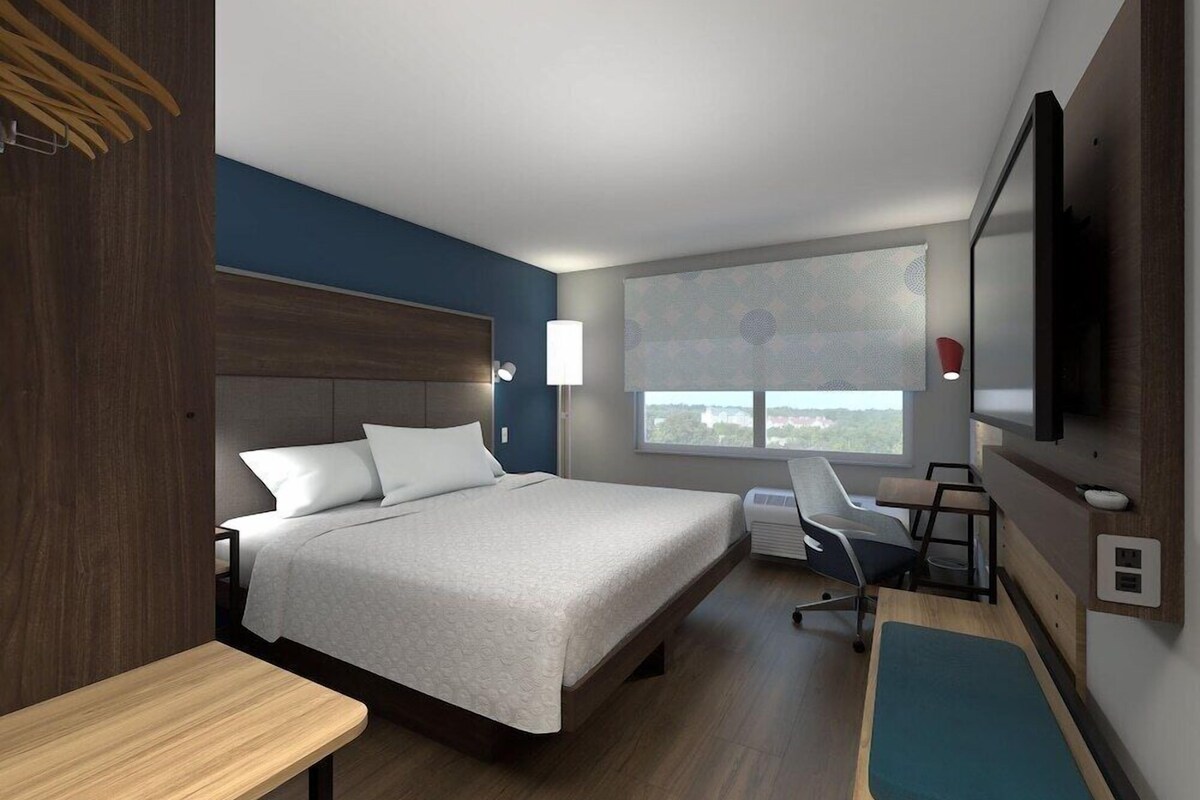 Een moderne hotelkamer met een groot bed, een bureau en een televisie.