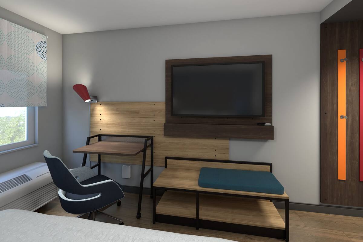 Une chambre à coucher moderne avec un lit, un bureau et un téléviseur fixé au mur.