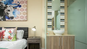 A modern bedroom with a bed, bedside table, and a large painting. - Comfortable and Stylish in Rosebank (Johannesburg)