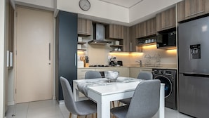 A modern kitchen with a dining table, chairs, a clock, and built-in appliances. - Comfortable and Stylish in Rosebank (Johannesburg)