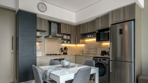 Una cucina moderna con tavolo da pranzo, sedie, frigorifero, microonde e lavatrice.