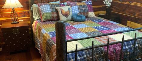 A wooden cabin-style room with a bed, a nightstand, a lamp, and a bench.