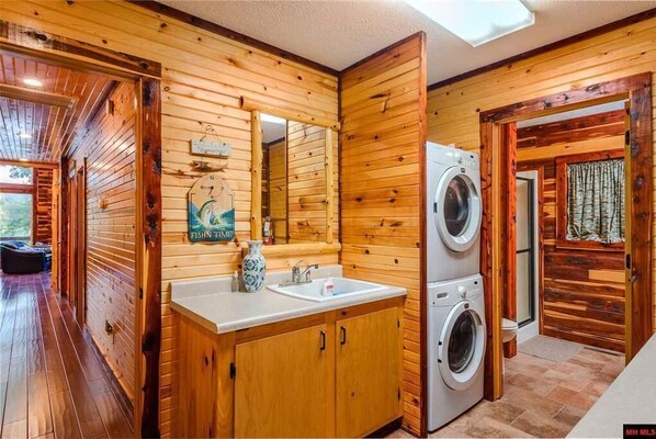 A wooden cabin interior with a wooden floor, a sink, a mirror, and a washing machine. - SECLUDED WHITE RIVERFRONT CABIN -SLEEPS 2-10, GREAT FAMILY & FISHERMEN GETAWAY (Norfork)