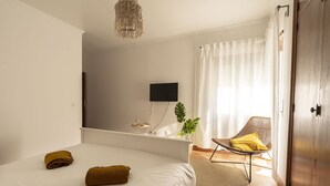 A bedroom with a bed, a chair, a television, and a plant. - Ericeira Paradise House & Suites (Mafra)