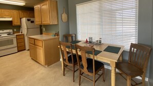 Une cuisine dotée de meubles en bois, d’un réfrigérateur, d’un four et d’un coin repas avec une table et des chaises.