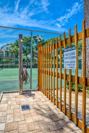 A fenced pool area with a sign indicating video surveillance and pool closure times.