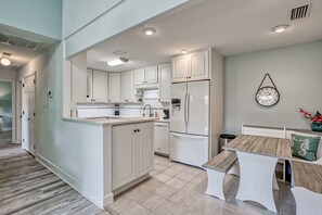 Enjoy meals in the kitchen with a central island and oven, adjacent to a dining area with a wooden table and comfortable seating.