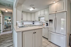 Kitchen features a sink, coffee maker, and stainless steel refrigerator on a light-colored countertop.