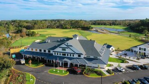 Un campo de golf con club house y zona de estacionamiento.