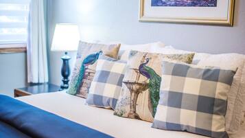 A bed with four decorative pillows, a lamp, and a framed picture on the wall.
