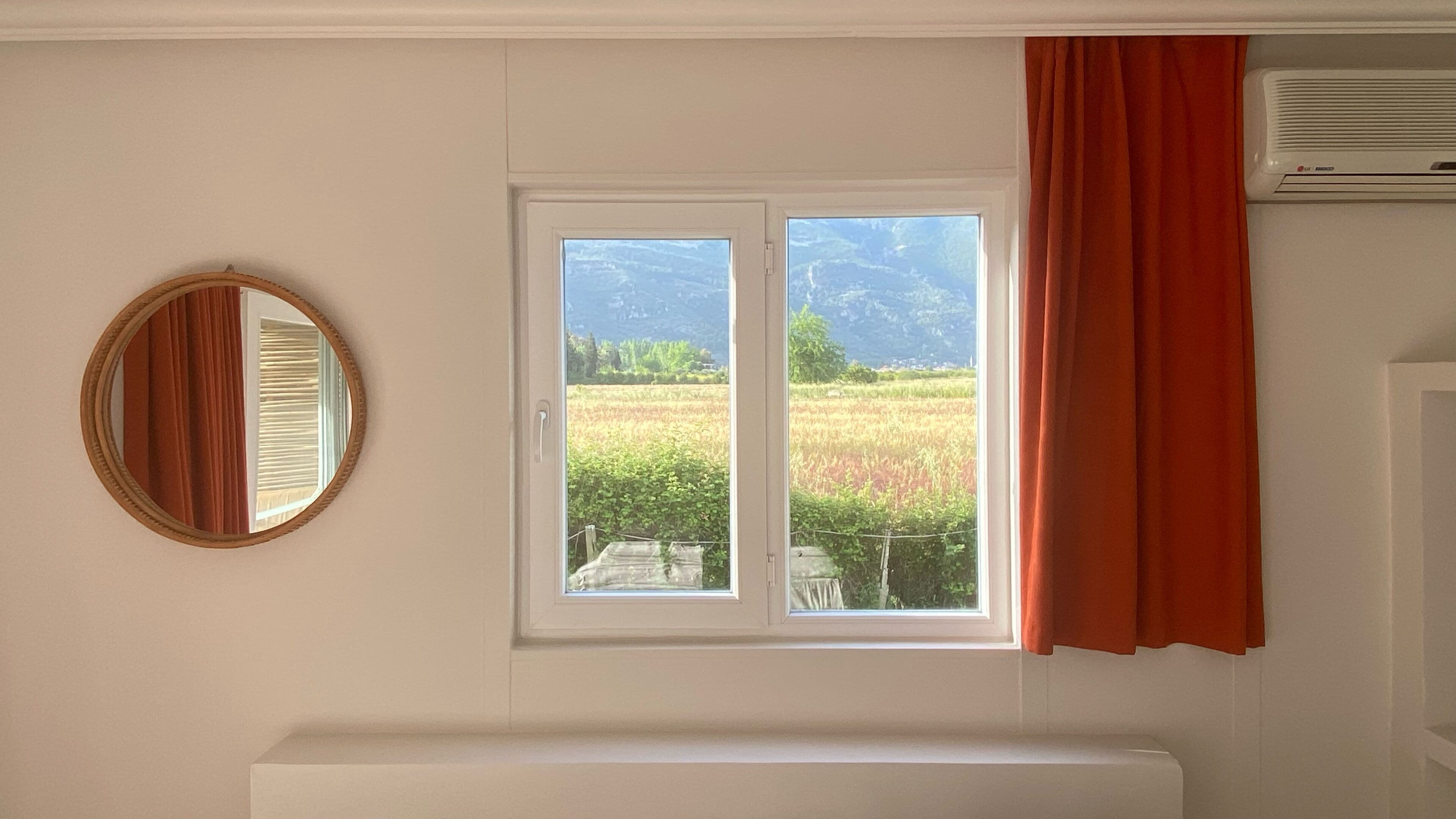 Una habitación con ventana, espejo y radiador.