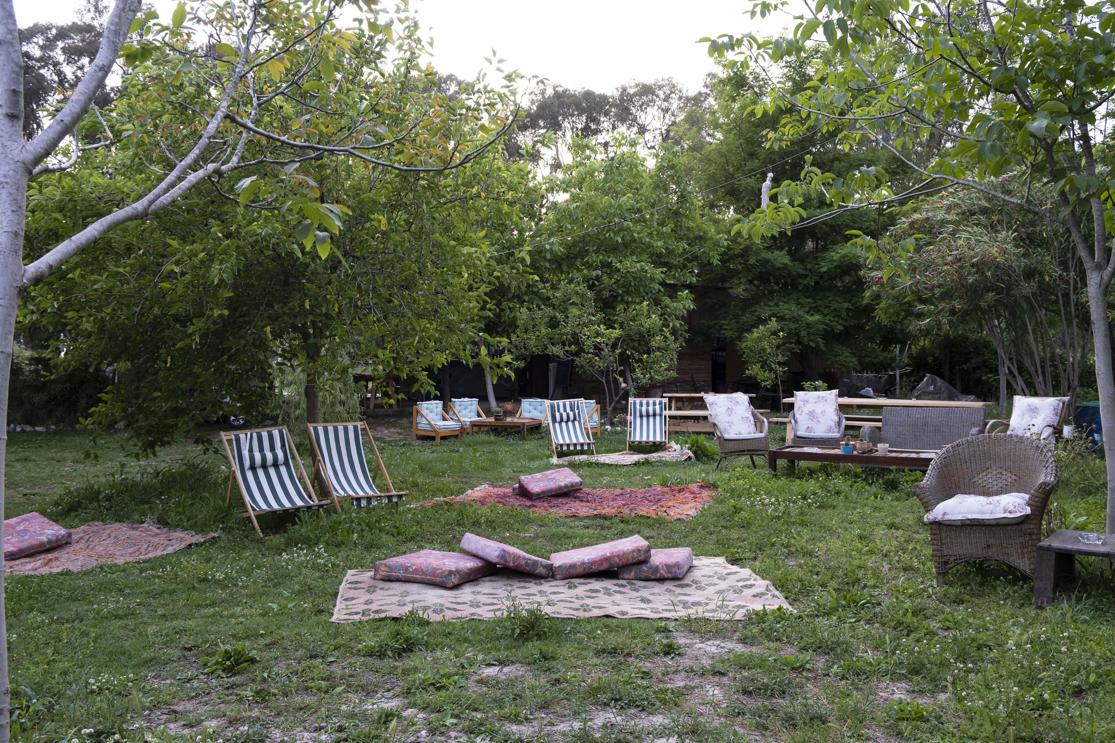 An outdoor seating area with multiple lounge chairs and a picnic table, surrounded by trees and greenery.
