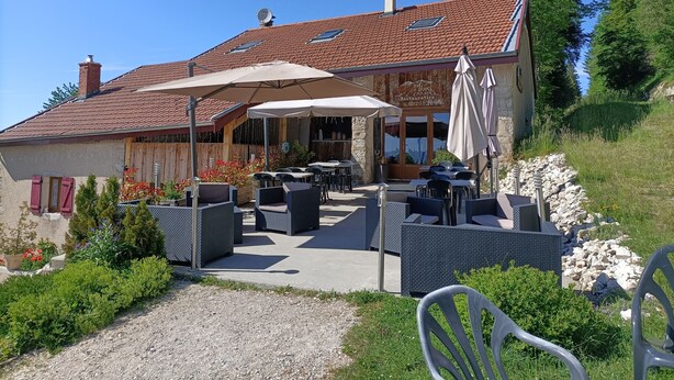 A restaurant with outdoor seating, a tiled roof, and a stone wall. - Gîte la grange de l'errance (Giron)