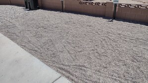 A gravel parking area with a guest parking sign, a trash bin, and a building with a stone facade. - Spacious Suite: Basement Apartment (Enoch)