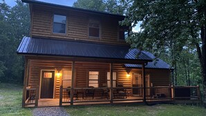 A two-story log cabin with a porch and a covered deck.