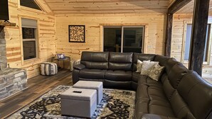 A cozy living room with a leather sofa, ottomans, and a fireplace.