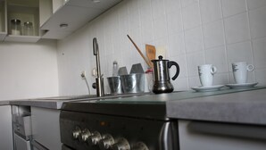 A kitchen with stainless steel appliances, white tiled backsplash, and various kitchen utensils on the counter.