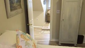 A bedroom with a bed, a door to another room, and a hallway leading to a staircase. - Explore Pittsburgh from a Modern, Hip Bungalow (Pittsburgh)