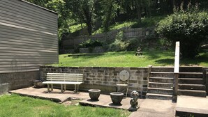 A patio area with a bench, two planters, and a small statue. - Explore Pittsburgh from a Modern, Hip Bungalow (Pittsburgh)