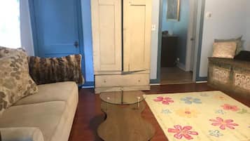 A living room with a beige sofa, a glass-top coffee table, a wooden cabinet, and a floral-patterned rug.