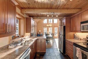 A spacious kitchen with wooden cabinets, a central island, stainless steel appliances, and large windows allowing natural light.