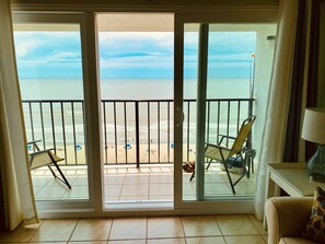 Une pièce dotée d’une porte-fenêtre coulissante donnant sur un balcon avec vue sur la plage.