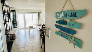Un vaste espace de vie comprenant un balcon, un coin repas et une décoration murale représentant une sirène.