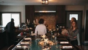 A long dining table set with plates, glasses, and cutlery, with a modern chandelier above. - Jeremys Mountain Chalet @jeremysmountainchalet (Anchorage)