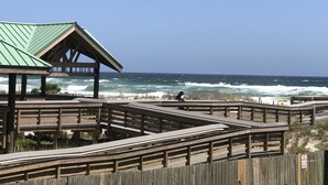 Una passerella in legno conduce a un gazebo con tetto verde che si affaccia sull'oceano.