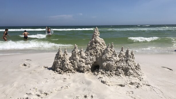 Una spiaggia sabbiosa con un grande castello di sabbia in primo piano.