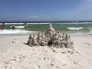A sandy beach with a large sandcastle in the foreground. - Little Piece of Paradise (Fort Walton Beach)