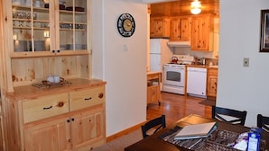 A wooden interior with a dining table, cabinets, and a kitchen area including a stove and refrigerator. - Eagle's Landing, is located in Island Park, ID, 35 miles from West Yellowstone (Island Park)