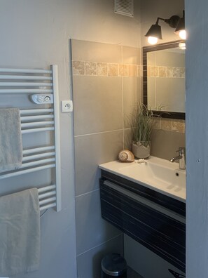 A bathroom with a white sink, a mirror, a towel rack, and a small trash bin. - Charming apartment, exceptional sea view, Les Restanques du Golfe de St. Tropez (Grimaud)