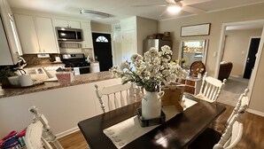 A dining area with a dark wooden table, white chairs, and a vase of white flowers.