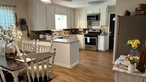 A modern kitchen with white cabinets, a central island, a microwave, and an oven.
