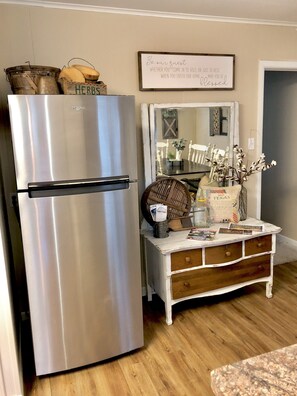 Enjoy meals in this kitchen with a dining table and chairs, a refrigerator, and a chest of drawers.