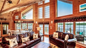 Een ruime cabin met houten wanden, grote ramen en lederen meubels.
