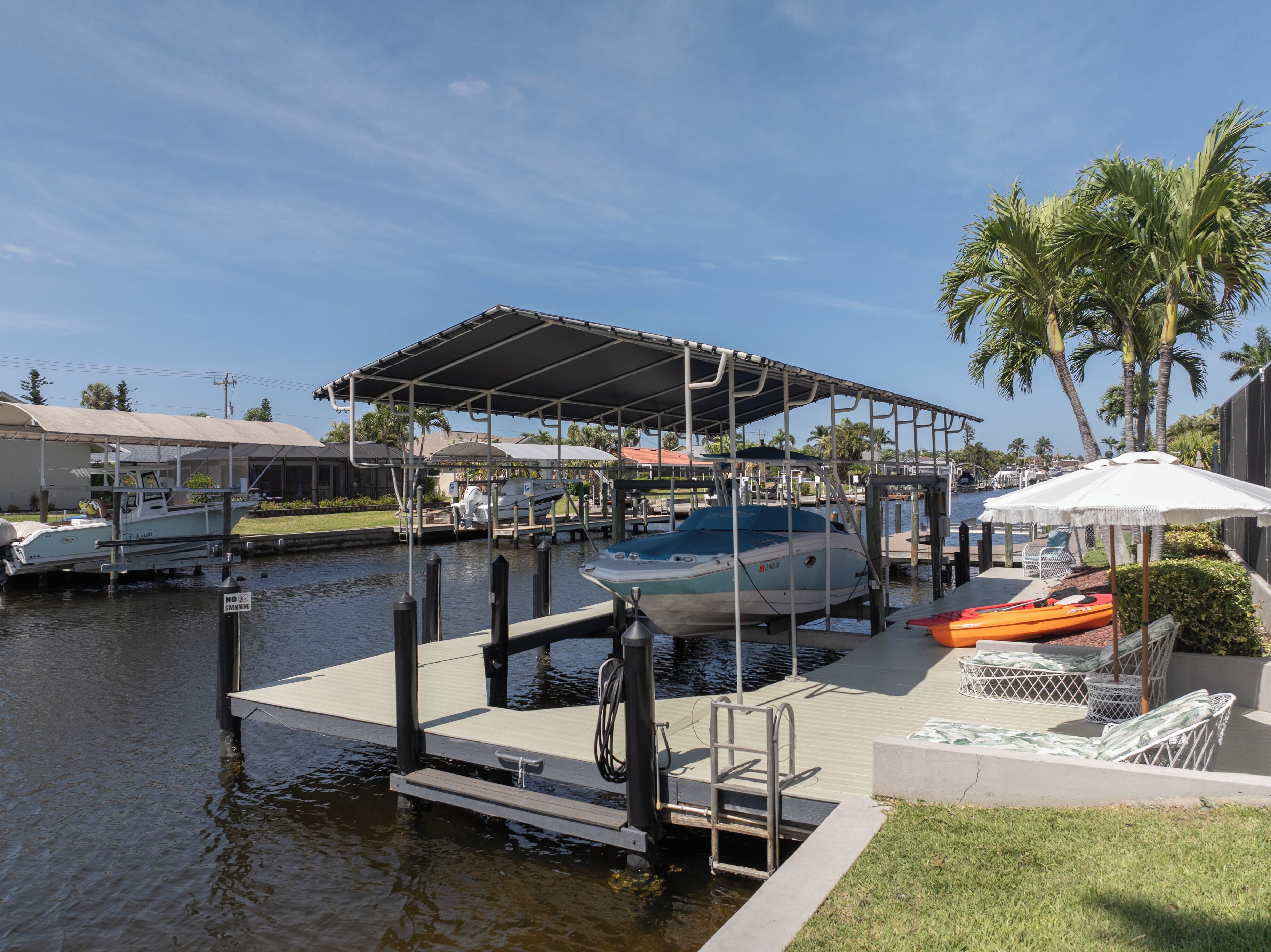 A marina with boats docked under a covered area, a kayak, and a lounge chair.