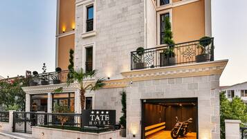 A multi-story hotel with a stone facade, a sign reading "TATE HOTEL", and a motorcycle parked in the driveway.