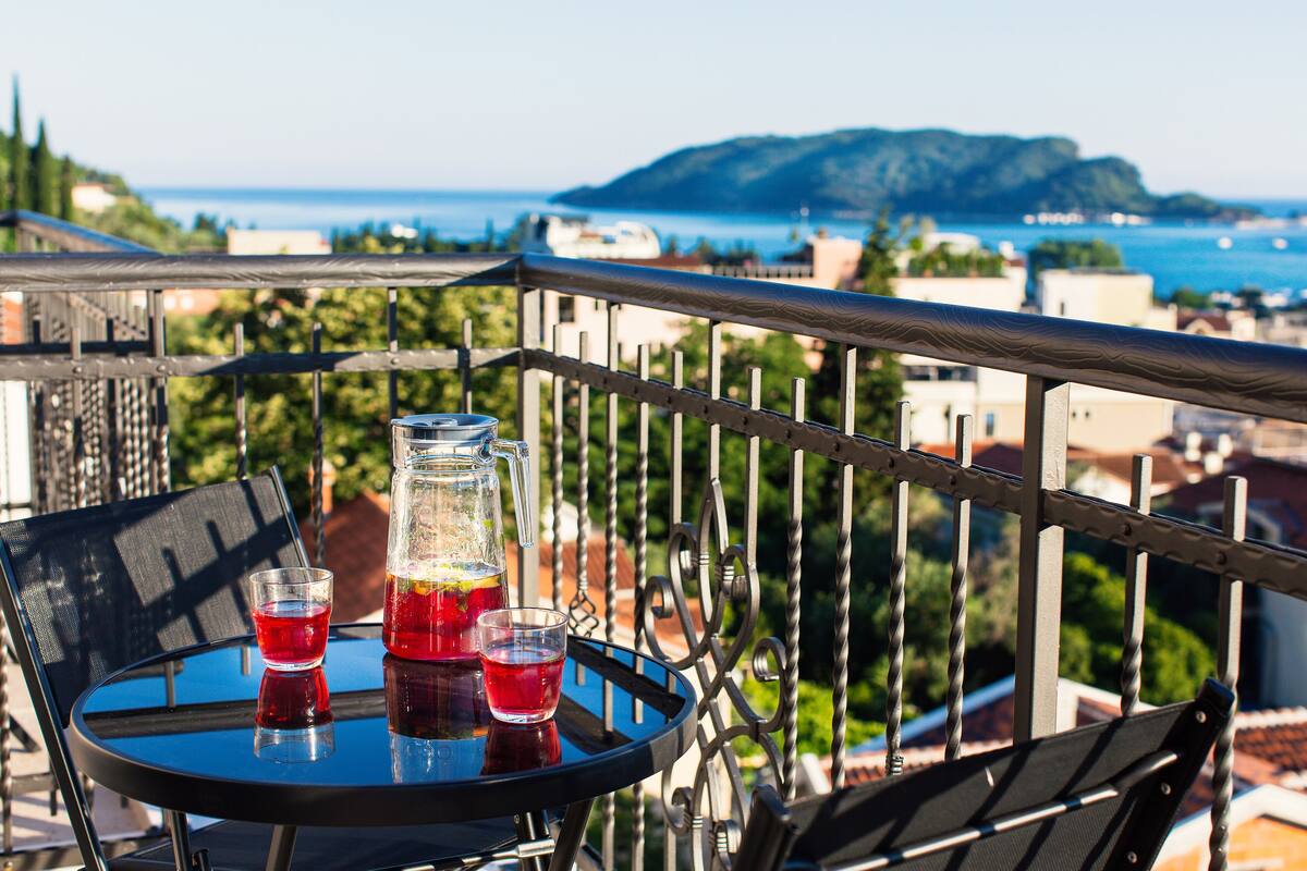 A balcony with a table, two glasses of red drink, and a pitcher.