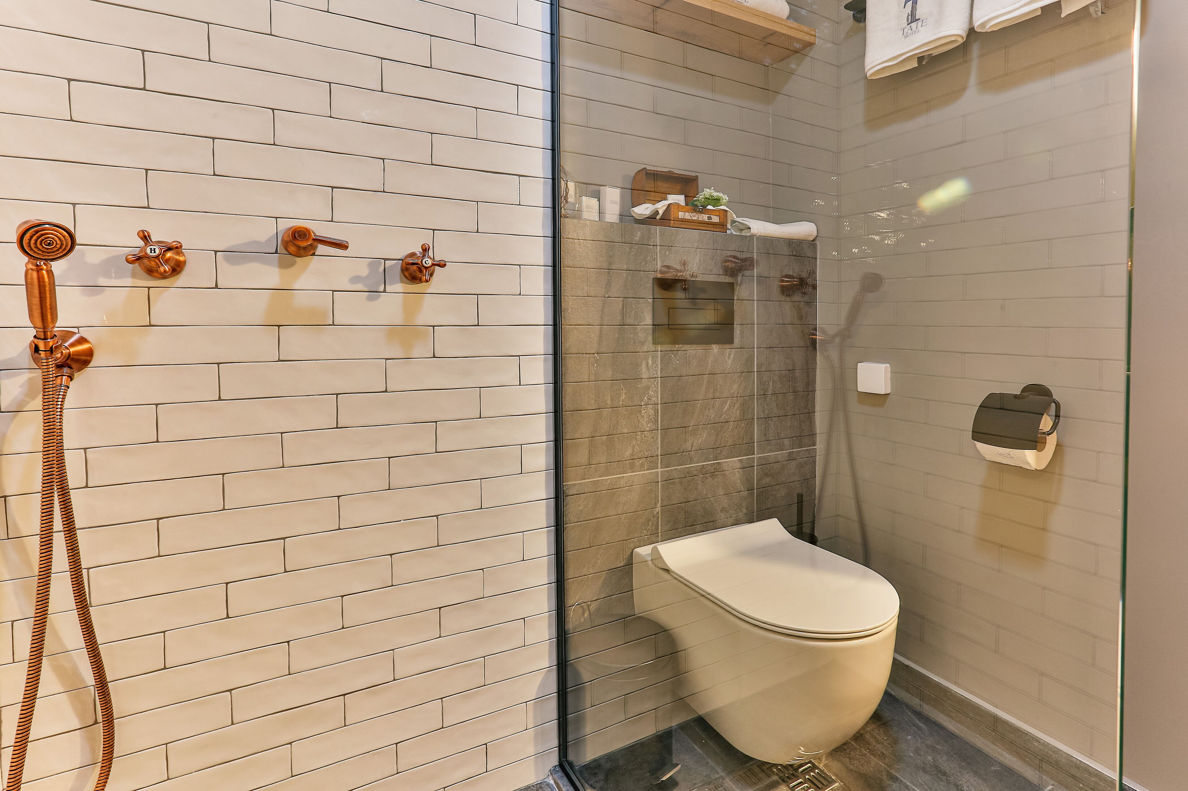 Un baño moderno con cabina de ducha de vidrio, inodoro blanco y toallero con toallas.