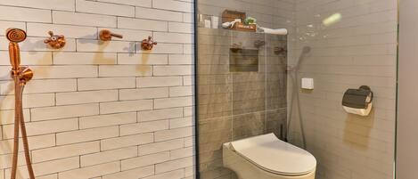 Un baño moderno con cabina de ducha de vidrio, inodoro blanco y toallero con toallas.